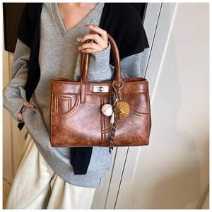 Détail d'un sac à main vintage marron avec breloques de baseball et fermoir métallique