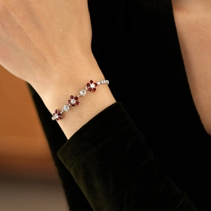 Macro view of silver floral bracelet with red heart-shaped stones and white zircon crystals