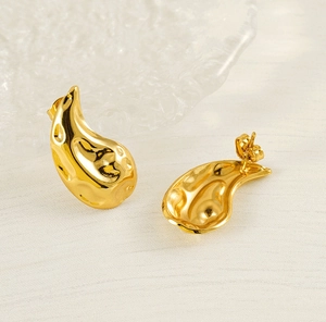 Macro detail of gold teardrop earrings with hammered texture and polished metal finish