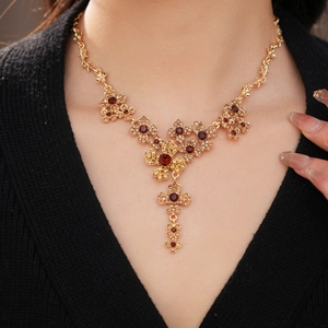 Detail of vintage gold flower necklace with red gemstones on model collarbone