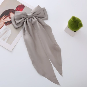 Detailed view of elegant grey satin bow hair clip with long silk streamers on white surface