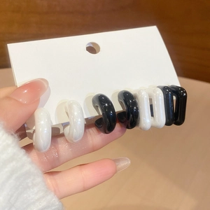 Close-up of minimalist black and white acrylic C-shaped earrings on a display card