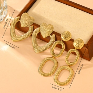 Vintage textured golden heart and geometric earrings displayed on a wooden tray