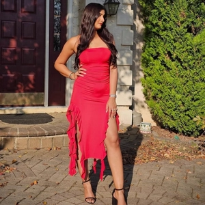 Detail of red strapless dress with ruched fabric and layered ruffles on the high slit