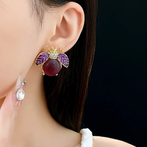 Detailed close-up of a vintage beetle stud earring featuring red and purple enamel with crystals