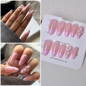 Detail von rosa French Almond Press-On Nails mit 3D-Blüten und Perlenakzenten