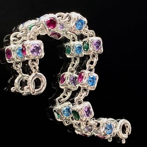 Close-up of silver chain featuring square crystals in red, blue, purple, and green colors