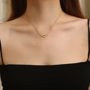 Gros plan d'un collier avec pendentif œil maléfique doré porté par un mannequin
