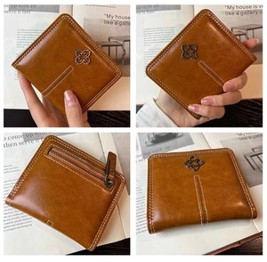 Brown leather wallet detail with clover charm, stitching and back zipper pocket