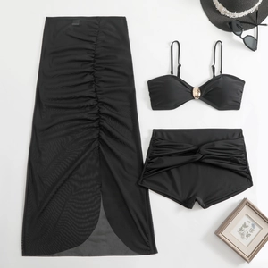 Detailed flat lay of black three-piece swimwear with gold hardware and mesh skirt