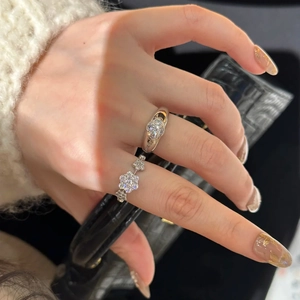 Macro shot of silver clover flower rings with sparkling zircon pavé on model's hand