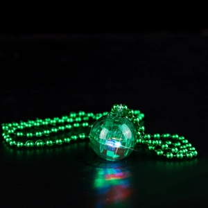 Close-up of a glowing green disco ball pendant with a bead chain on dark background