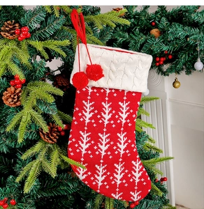 Detail of red knit Christmas stocking with tree pattern hanging on a decorated tree