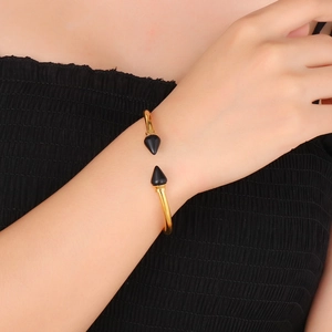 Close-up of golden stainless steel rivet bangle with turquoise spikes on female wrist