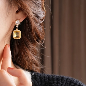 Detail of model wearing 18K gold plated square gem earrings with vintage palace style accents