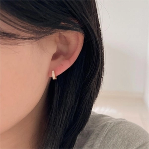Close-up of a model wearing a gold hoop earring set with baguette-cut clear crystals