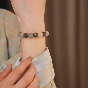 Détail macro d'un bracelet en perles de cristal coloré porté avec une manche brodée élégante