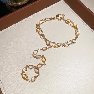Close-up of gold tassel necklace with multicolored oval resin gemstones on a display tray