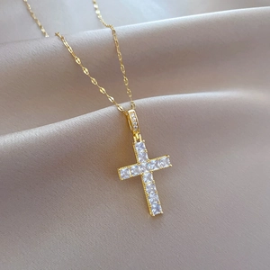Macro shot of gold cross necklace featuring square cut cubic zirconia and fine chain
