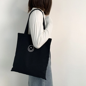 Black canvas tote bag for women featuring a minimalist white smiley face print
