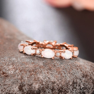 Détail macro de la bague en or rose avec opales de feu ovales et pierres en zircon