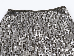 Detailansicht silberner Pailletten auf einem schwarzen Mesh-Gummibundrock mit Metallstruktur