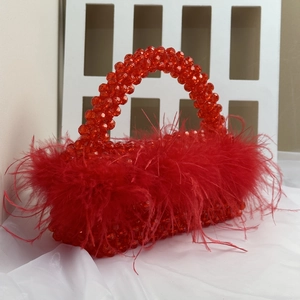 Detail of red handmade beaded handbag featuring elegant ostrich feather fringe