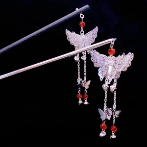Silver butterfly hair stick with long tassels and red beads on a black background