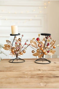 Pair of decorative golden iron candle holders with red berries on a wooden table