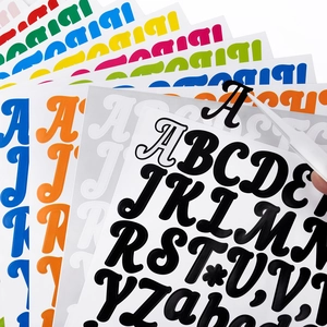 Gros plan d'une pince retirant un autocollant de lettre noire d'un ensemble alphabet coloré