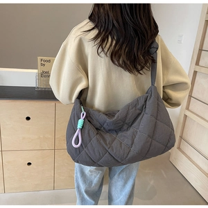 Macro view of charcoal grey quilted tote bag with knot detail and colorful woven pendant