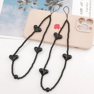 Dual pack of black beaded heart phone wrist straps on a pink case and magazine