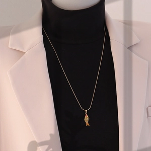 Détail du pendentif carpe koi 3D vintage sur une chaîne serpent dorée portée sur un pull