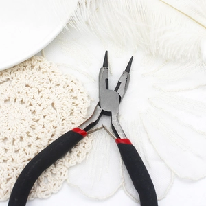 Detail of jewelry making pliers with black and red handles on a white decorative background