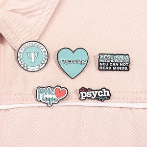 Detailed view of psychology theme enamel pins on light pink denim fabric background
