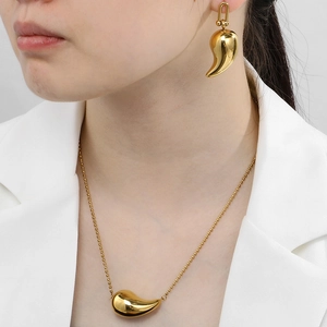 Parure collier et boucles d'oreilles goutte dorées sur mannequin en costume