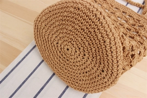 Detailed close-up of the dense circular weaving pattern on the bottom of a khaki woven bag
