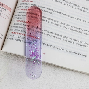Detail of a pink and purple gradient resin bookmark with glitter on an open book