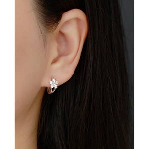 Macro shot of silver flower hoop earring with sparkling crystals on a model's ear