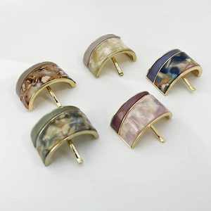 Detail of five marble patterned resin ponytail hair hooks with gold metal frames