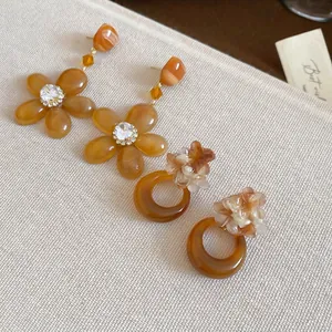 Amber resin flower drop earrings with rhinestone accents on a neutral fabric background