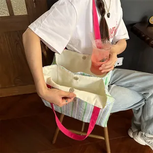 Dettaglio di borsa tote in tela a righe con manici rosa vivaci e chiusura magnetica