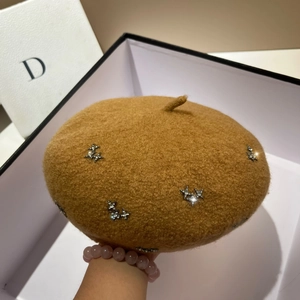 Detailed macro of camel wool beret featuring shiny silver star rhinestone decorations