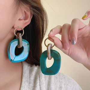 Detailed close-up of retro turquoise marbled resin hoop earrings with gold rings.
