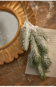 Close-up of frosted artificial pine branch with snow effect on a rustic wooden desk