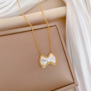 Close-up of a gold bow pendant necklace with white pearl inlay on a jewelry box