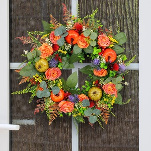 Autumn wreath with orange roses and pumpkins hanging on a glass door for fall decor