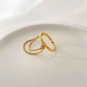 Detailed macro of gold minimalist ring featuring dual snake chain tassel fringe accents