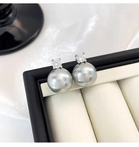 Macro shot of elegant grey pearl stud earrings with sparkling crystals on velvet padding