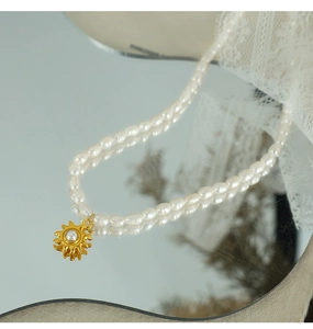 Detail of freshwater pearl necklace with gold sunburst pendant on a mirror